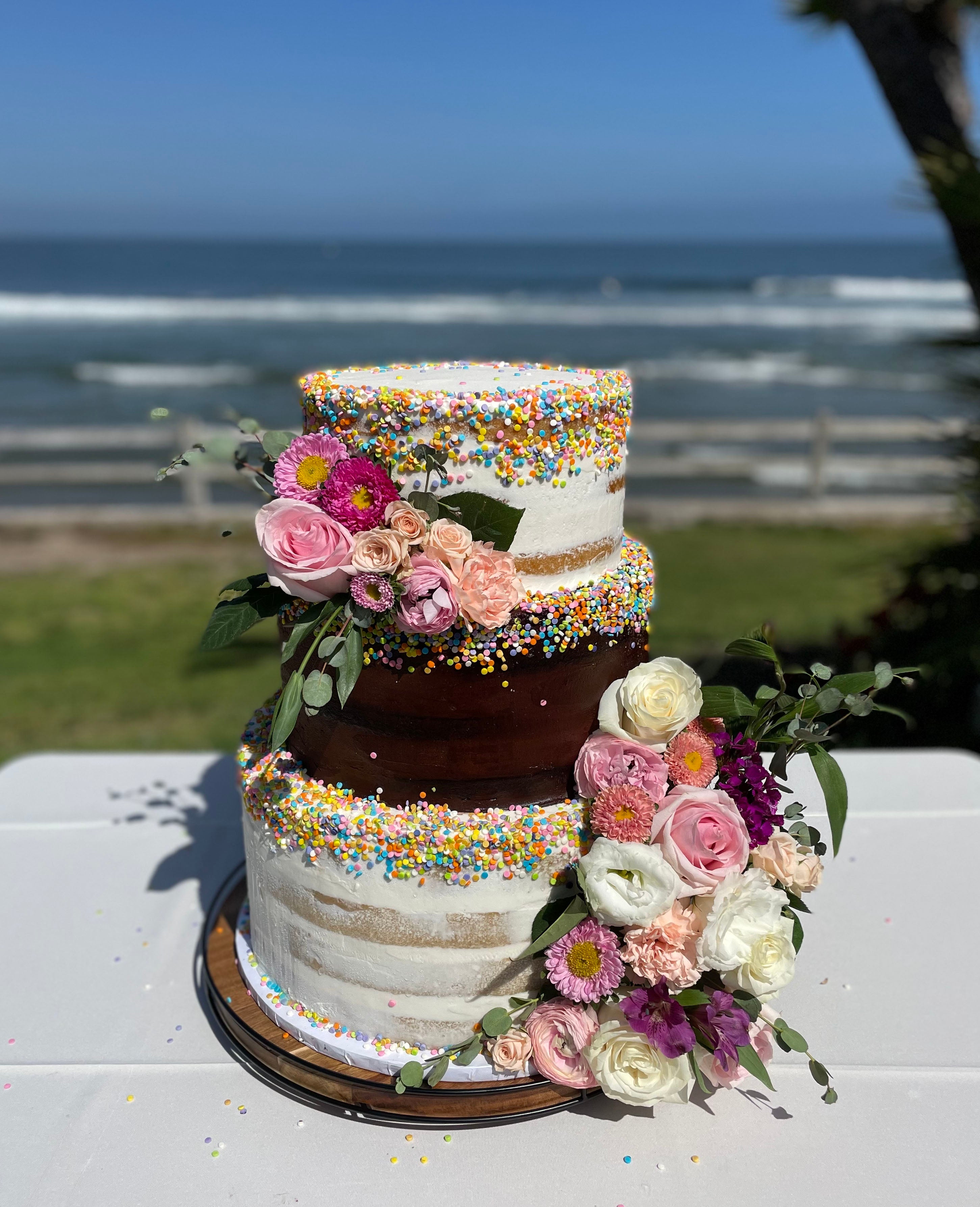 semi-naked wedding cake in chocolate and vanilla with sprinkles and flowers